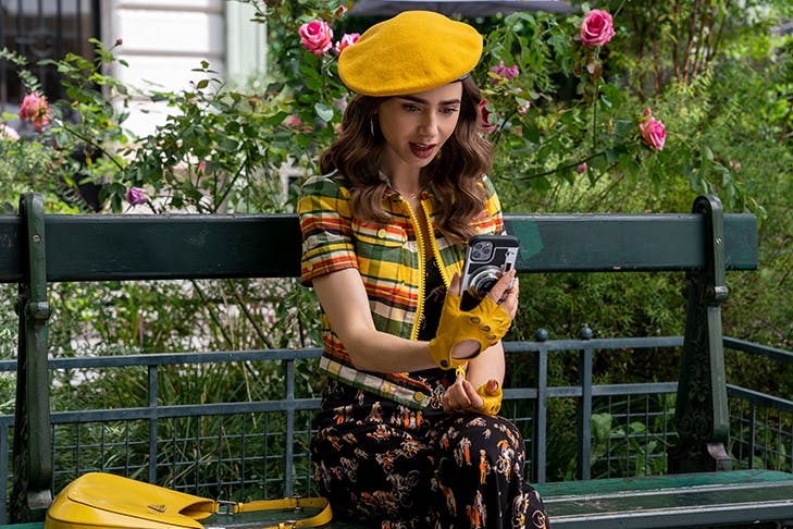 woman sitting on park bench wearing beret and taking a selfie